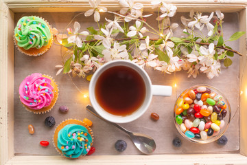 morning tea with cakes, on a tray with a garland and a blooming twig. morning mood