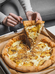 Pizza with pear and dor blue cheese in delivery box. Female hands
