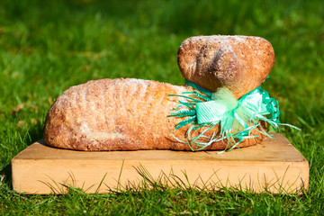 Easter lamb cake on a wooden kitchen cutting board lying on the green grass