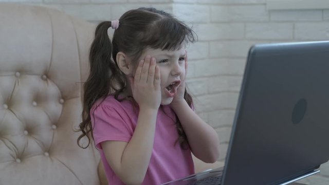 Shock in the computer. Forbidden Internet. The little girl is horrified by what she saw in the computer monitor.