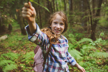 kid girl exploring summer forest, playing with wild ferns. Teaching kids to love nature, summer camping concept