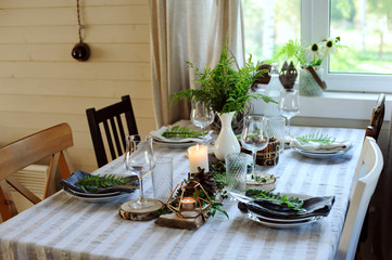 rustic country kitchen interior with festive table setting for summer dinner in natural green and...