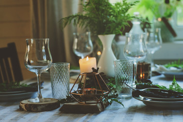 cozy evening family dinner in rustic style. Table summer setting in natural style with wild ferns in wooden cottage or country house.