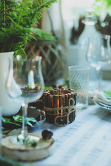 rustic festive table details with wild ferns, handmade decoration and candles. Country home dinner in summer evening.