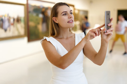 Woman photographing painting in museum