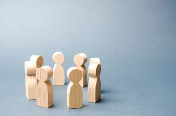 People stand in a circle on a gray background. Wooden figures of people. A circle of people. discussion, cooperation, cooperation. Communication. Business team, teamwork, team spirit. Selective focus