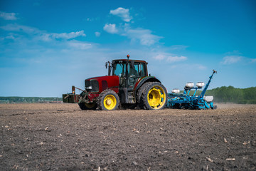 A large tractor in the field prepares a land for planting