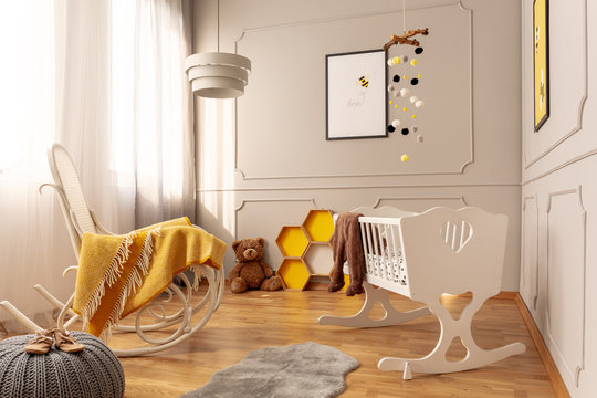White wooden cradle and rocking chair with cozy yellow blanket in bright grey toddler room
