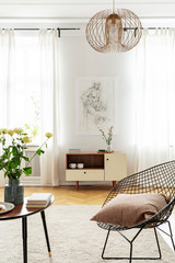 Industrial metal armchair with pillow next to wooden coffee table in bright room