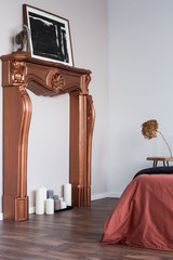 Modern coppery fireplace portal with candles and artwork in white room