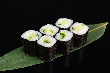sushi rolls with cucumber on black background