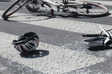 Kid's helmet and broken car's mirror next to broken bicycle on pedestrian crossing