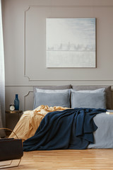 Pastel blue painting on grey wall of trendy bedroom interior