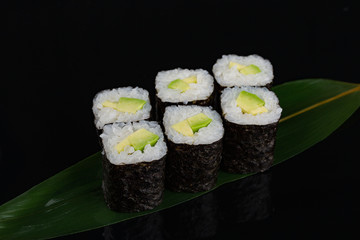 Sushi rolls with avocado on banana leaf