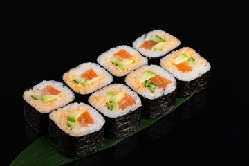 Maki sushi with avocado, cucumber and salmon on banana leaf