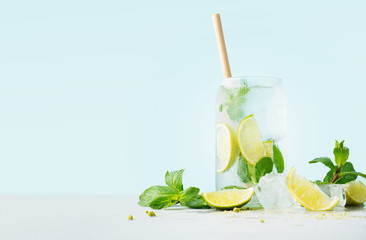 Close up of glass of tropical mojito cocktail on cyan pastel background with copy space. Summer time vacation concept.