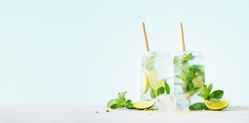Close up of glasses of tropical mojito cocktail on cyan pastel background with copy space. Summer...