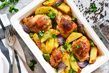 Hot spicy chicken with potatoes and broccoli baked. Concrete background. View from above.