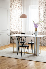 Sheer curtains with pattern on the windows of a classy dining room interior with a pink pendant light and a marble table