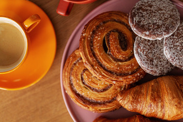 Top view of sweet rolls and coffee on table set for breakfast