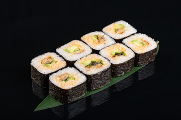 sushi with eel, avocado and cucumber on banana leaf