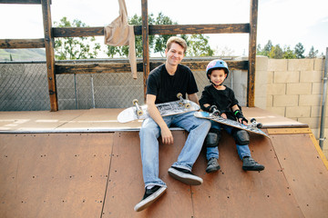 Young boy and skateboarding instructor smile for photo on half pipe