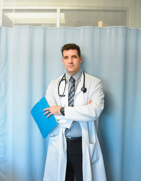 Doctor in white coat standing in front of hospital room curtain.