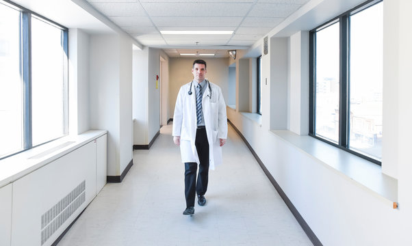 Doctor in white coat walking down the hallway in a hospital.