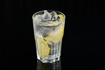 cold cocktail with lemon. A glass of dew drops. Freshness, alcohol, bar. Black background
