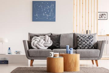Blue abstract painting on white wall of contemporary living room interior with grey settee with pillows