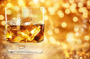 Glass of whiskey and Ice on wooden table on blurred background