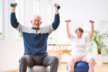 Senior man exercising with weights in his retirement home