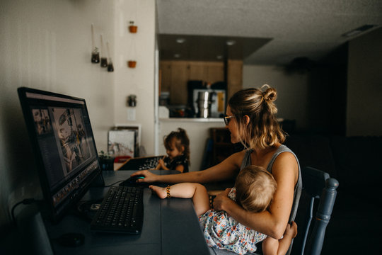 Working mother multitasking on the computer and holding baby