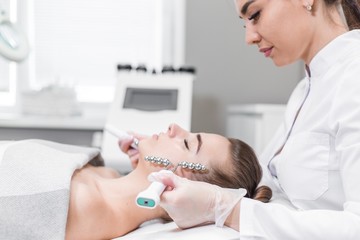 Beautiful girl on the procedure of therapeutic facial massage side view. Body care at the Spa