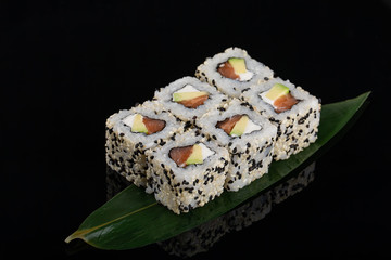 Uramaki maki sushi, two rolls on black background. Philadelphia cheese, tuna, cucumber and sesame