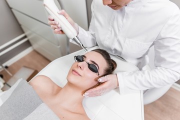 Laser cosmetic procedure of skin rejuvenation. Girl on a visit to a beautician and a beauty salon