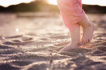 Feet of little girl in sand at beach in evening light with toe nails