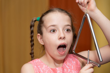 Mädchen mit Triangel schaut überrascht  