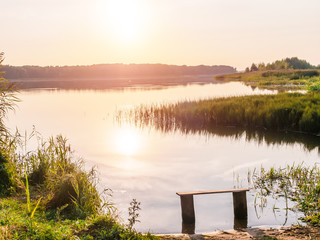 Empty bench near the river at sunset. Away from the hustle and bustle. Sun setting over the...