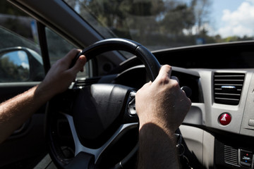 the man hold steering wheel and drive a car.