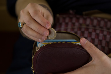the woman put the money in the moneybox or wallet for saving.