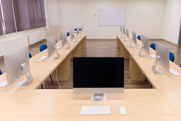 Modern office with computers on desks. Empty computer room in college. Interior of classroom with computers. Concept of corporate working space.