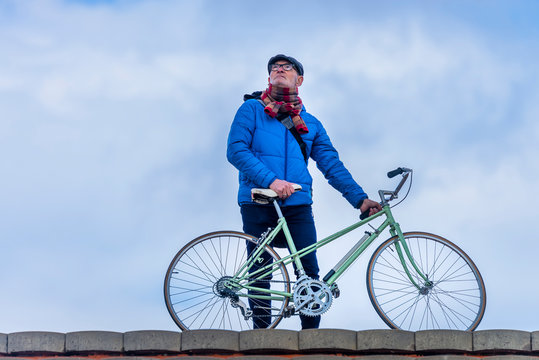 Front view of senior man standing with bike while looking away outdoor