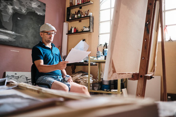 Man working as painter looking at reference image for new painting
