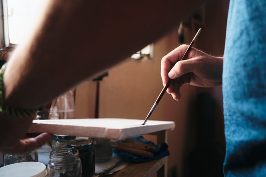 Male artist testing acrylic paint and brush on canvas for new work