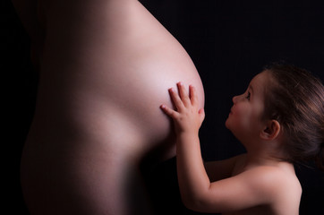 Young attractive mother with her toddler daughter. Seventh month