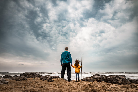 Father and daughter during storm at beach stand unafraid