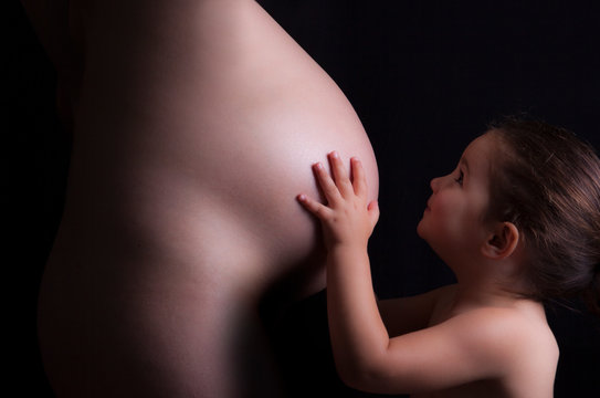 Young attractive mother with her toddler daughter. Seventh month