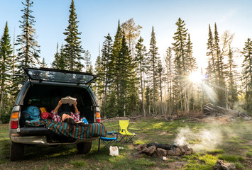 Good Spot to Read - Young woman reading wile car camping in forest