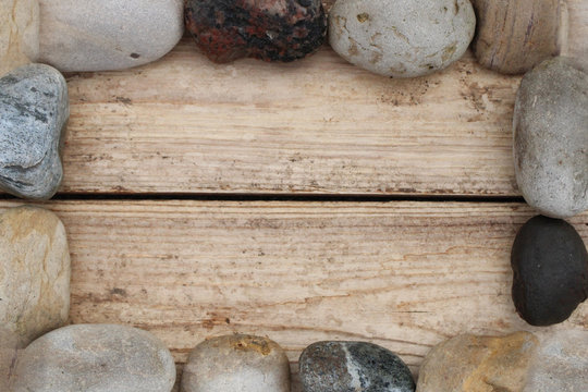 Weathered wood boards background with river rocks forming a frame/border.